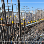 一排亮黃色的『鋼筋保護套』，包覆尖銳的鋼筋防止施工人員受傷，也防止鋼筋磨損和損壞。