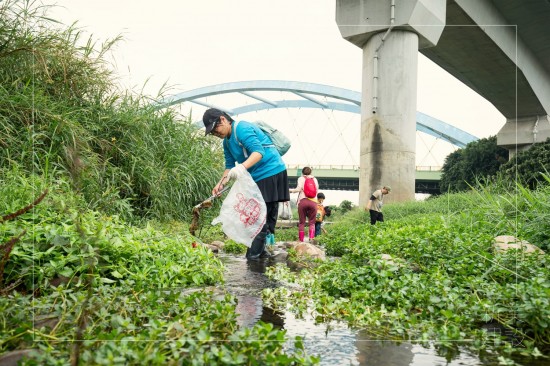 彎下腰、踏進溪流，撿起水中的垃圾殘骸，還給魚兒一個安全舒適的家園。