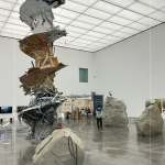 走進綠美圖，五個錯落有致的展廳，在 4 到 10 公尺的高低起伏間，構築出極簡純淨的「白盒子」空間。光線從高窗輕柔灑落，讓每一件大型創作都能在此自由呼吸。